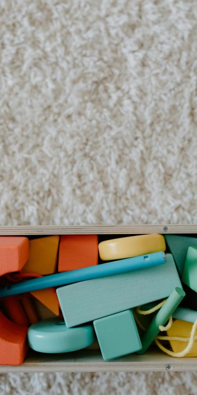A collection of colorful and sustainable wooden educational toys on a textured carpet.