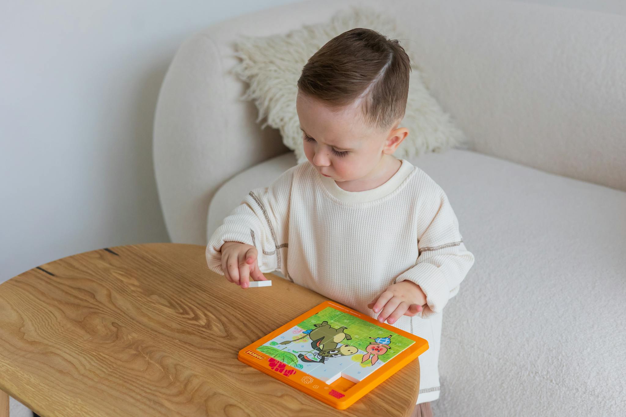A young child playing with an educational puzzle on a table indoors.