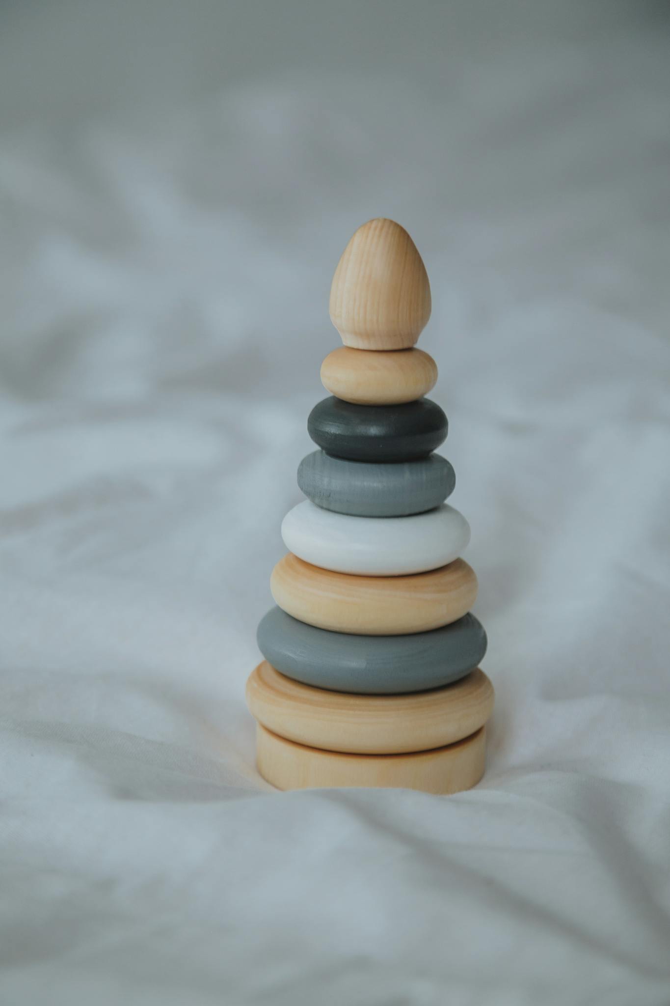 Minimalist photo of a wooden ring stacker toy set against a soft background, ideal for child development themes.