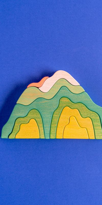Vibrant wooden mountain toy set against a vivid blue backdrop, highlighting a playful and creative concept.