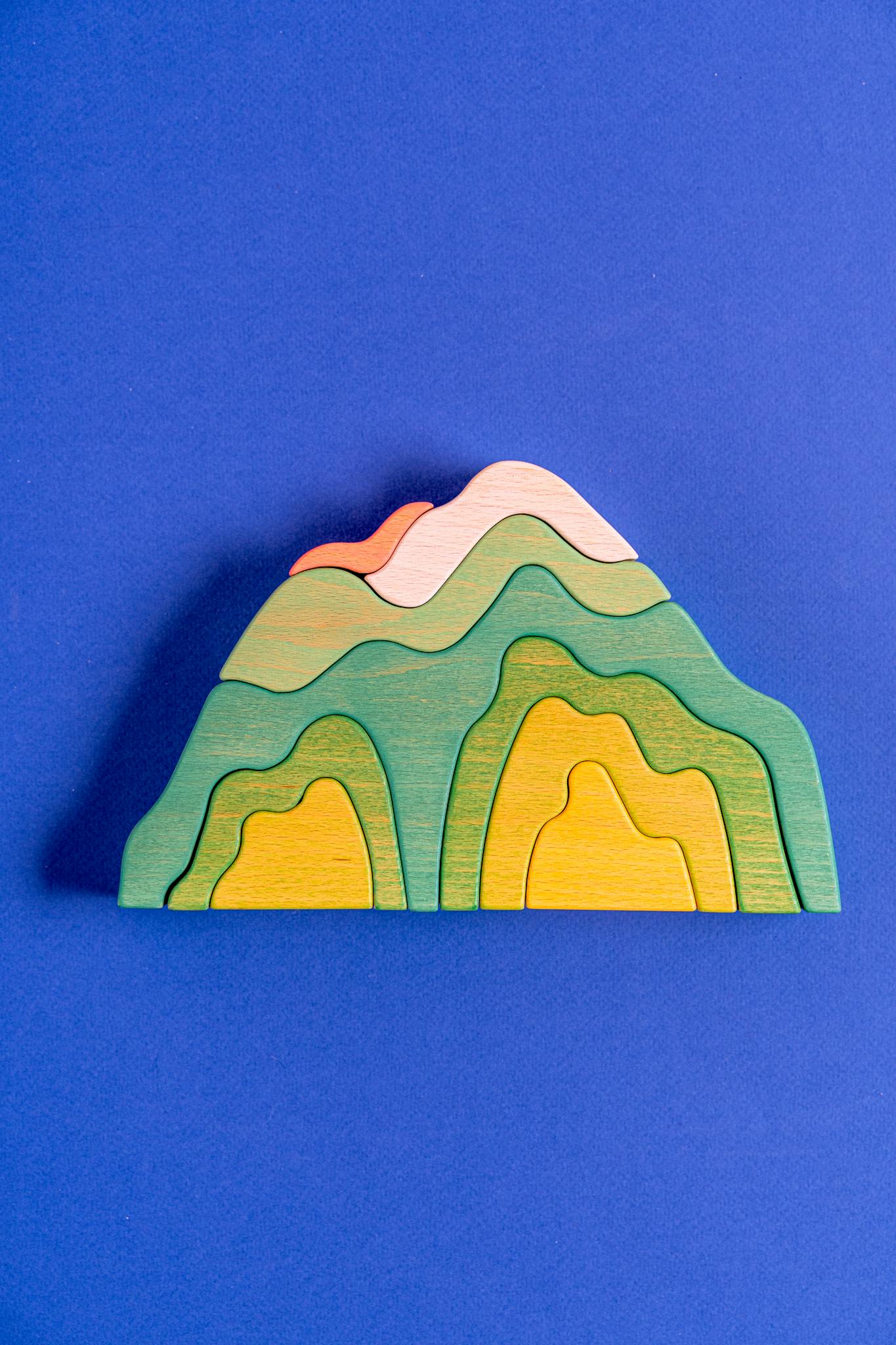 Vibrant wooden mountain toy set against a vivid blue backdrop, highlighting a playful and creative concept.